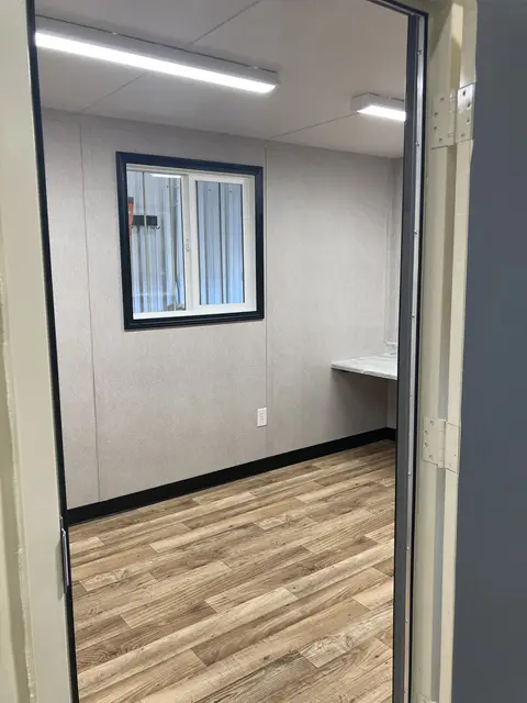 View into the finished 12-foot office area of OS-365 with wood-look flooring, window, lighting, and workstation