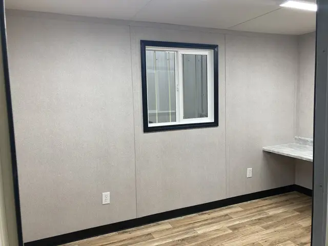 Finished interior of the O-362 on-ground office with wood-look flooring, window, electrical outlets, and workstation
