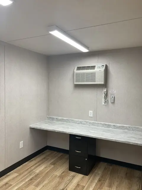 Built-in workstation inside the O-362 on-ground office with counter, filing pedestal, lighting, outlets, and air conditioner