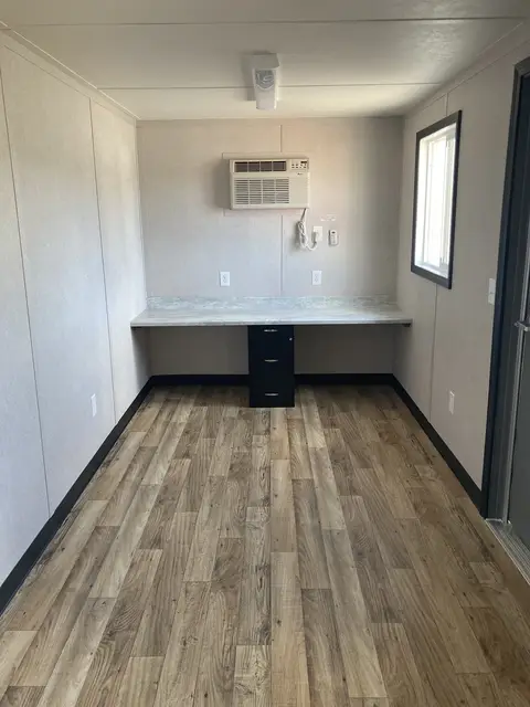 Built-in workstation inside the O-366 on-ground office with counter, filing pedestal, air conditioner, lighting, outlets, and window