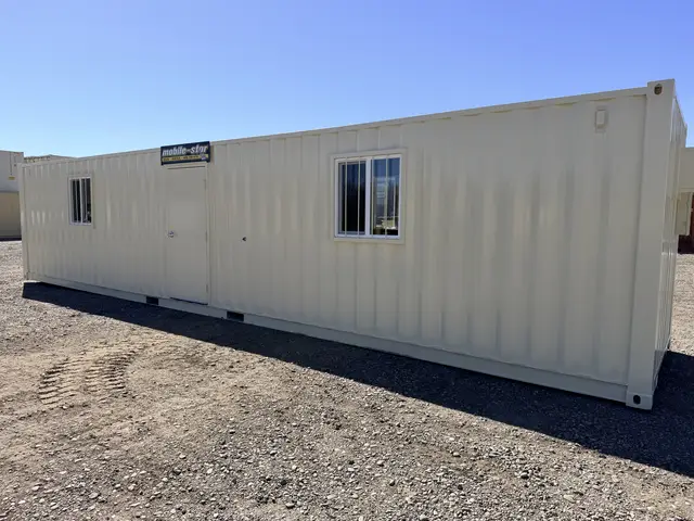 Front exterior of the O-370 8 by 40 foot on-ground office with personnel door and two barred windows