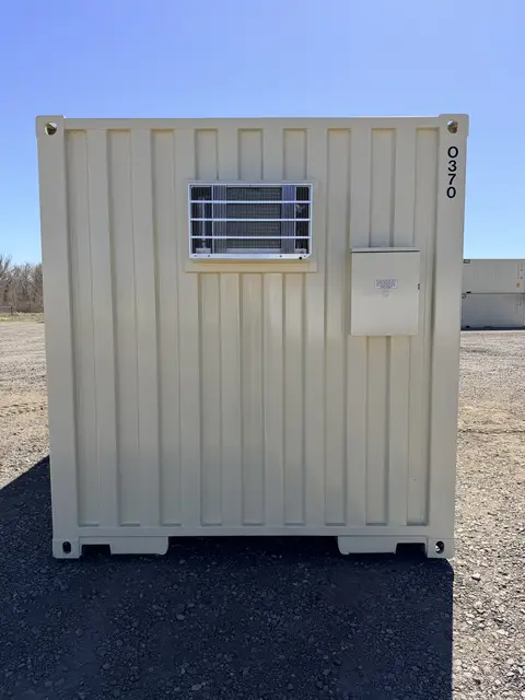 End wall of the O-370 on-ground office showing the protected air conditioner and exterior electrical panel