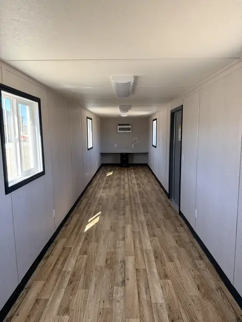 Full-length finished interior of the O-370 on-ground office with multiple windows, lighting, outlets, air conditioner, and workstation