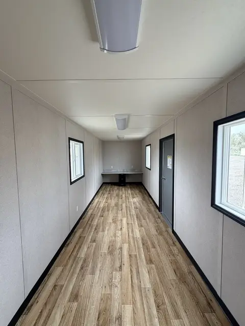 Open 30-foot workspace inside O-372 with wood-look flooring, multiple windows, lighting, outlets, and built-in workstation