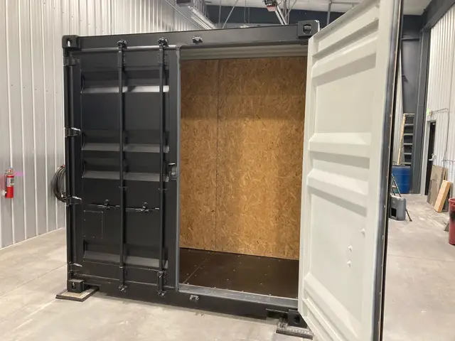 Charcoal container conversion with cargo doors open to an OSB-lined storage bay