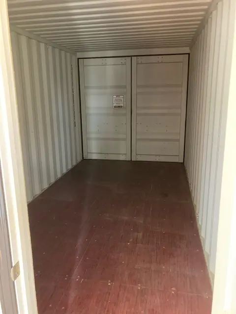 Shipping container interior with plywood floor and interior double doors at the far end