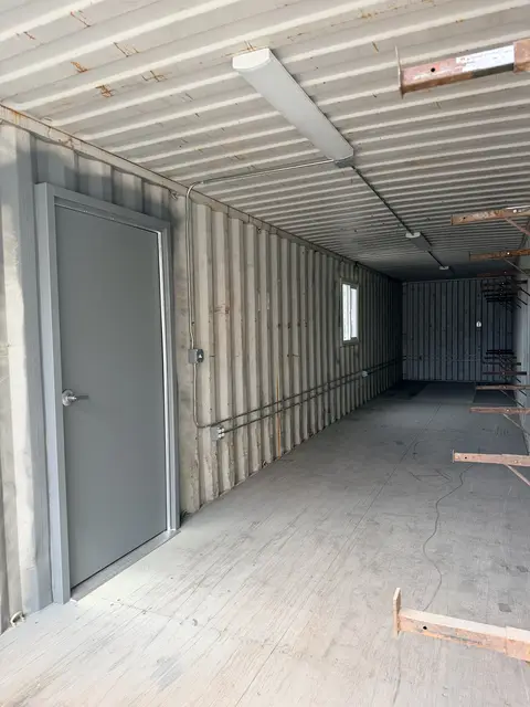 Container interior during rough-in with exposed framing supports and personnel door