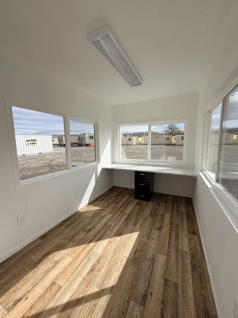 Angled exterior view of a compact guard office with wraparound windows