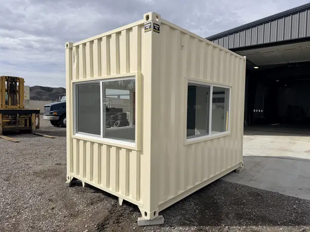 Compact guard office with personnel door, large windows, and wall air conditioner