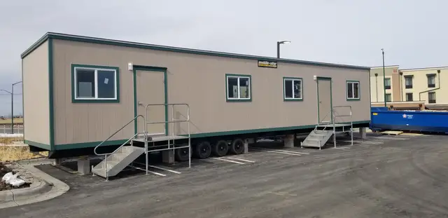 Large tan and green mobile office trailer with two entrances and aluminum stairs