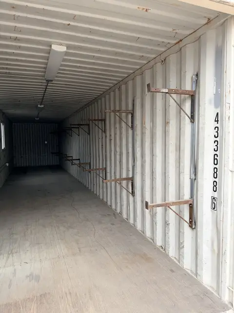 Long finished container office interior with windows, desk, resilient floor, and air conditioner