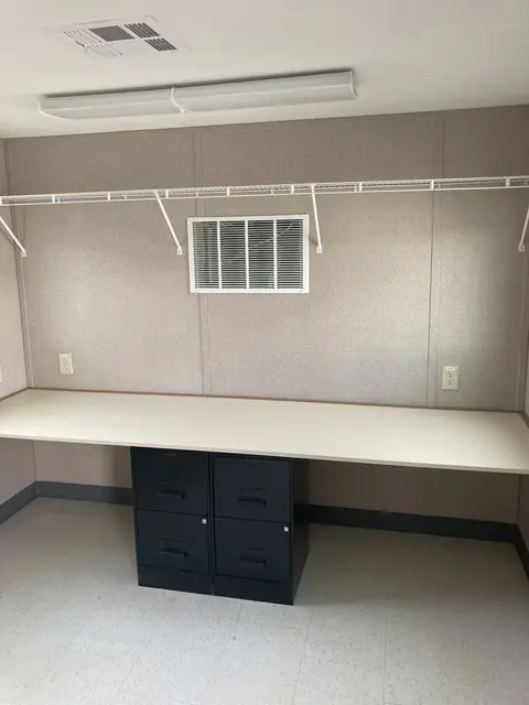 Office trailer workstation with long counter, filing cabinets, shelving, and electrical outlets