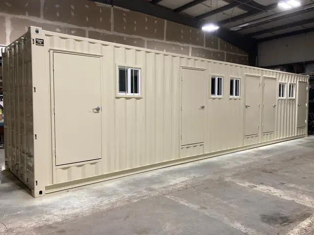 Long custom container build with four personnel doors and multiple barred windows