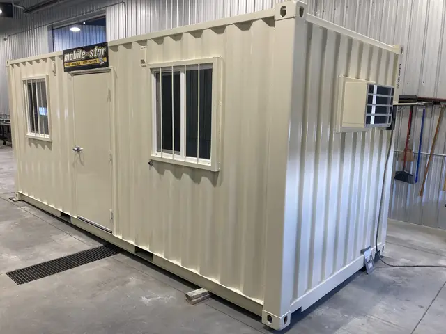 Sand-colored 20-foot container office with personnel door, barred windows, and air conditioner