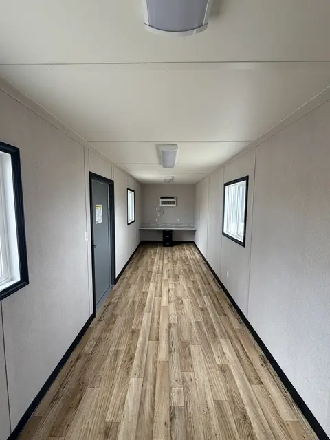 Sand-colored container office with personnel door, two barred windows, and Mobile-Stor branding