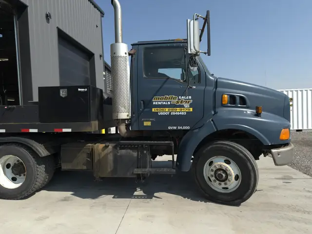 Profile view of Mobile-Stor's branded blue delivery truck outside the shop