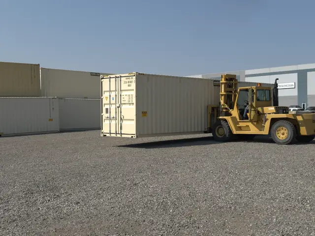 Forklift transporting a full-size shipping container across the gravel yard